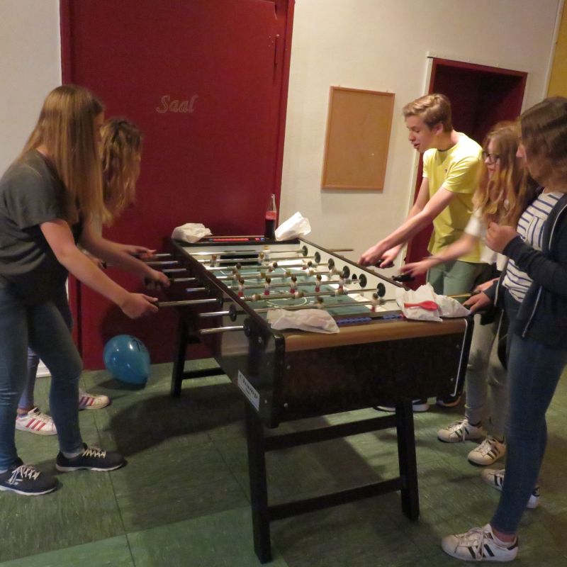 Kinder und Jugendliche stehen im Jugendclub Werden und spielen zusammen Kicker.