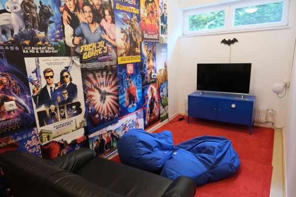 Playstationraum mit bunter Posterwand, Sofa, Sitzsack und Playstation samt Bildschirm.