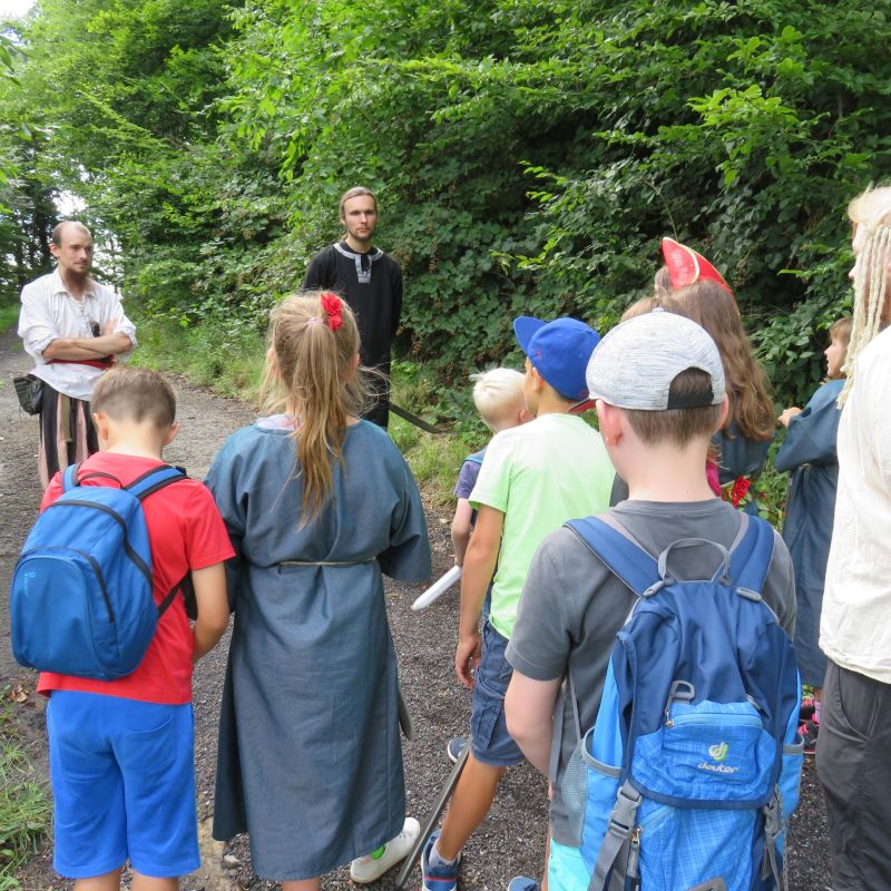 Kinder sind auf Schnitzeljagd und hören den Anweisungen der Ralleyführer zu.
