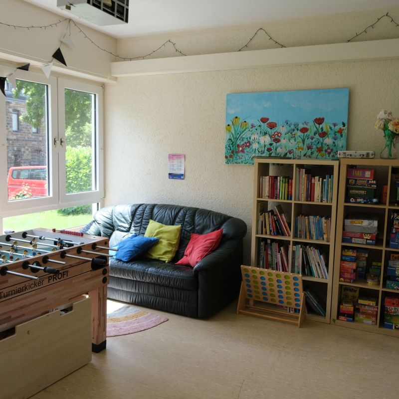 Offener Bereich mit Kickertisch, Sofa und Bücherregal.