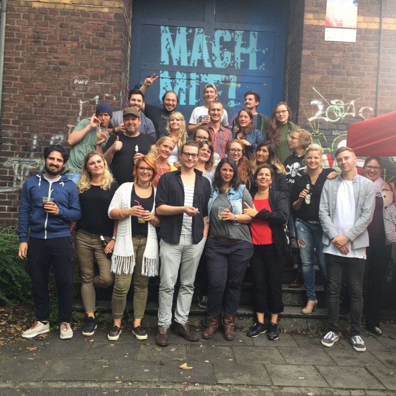 Um die 20 Menschen stehen vor der Eingangstür des Youth Cultures und machen ein Gruppenfoto.