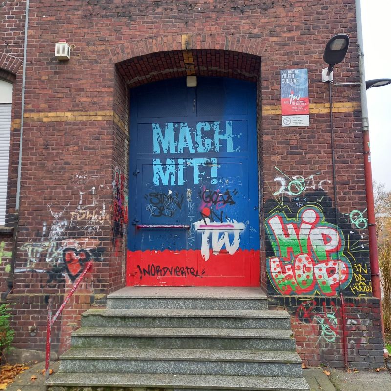 Eingangstür Youth Culture. Oben blau und unten rot mit dem Schriftzug 'Mach mit!'
