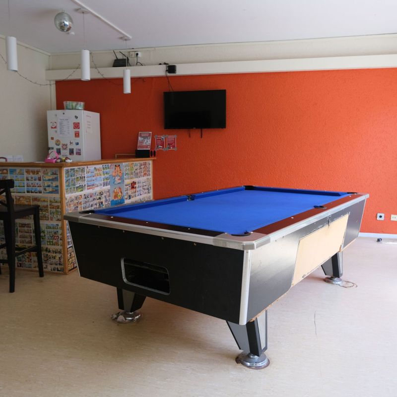 Offener Bereich mit Billiardtisch und Kiosktheke mit zwei Hochstühlen.