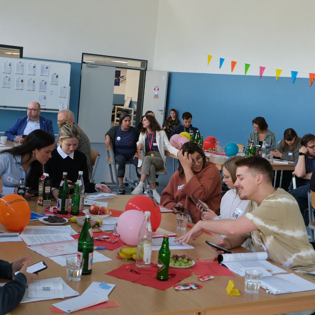 Jugendwerksmitglieder auf der Konferenz, die zusammen an einem Tisch sitzen.