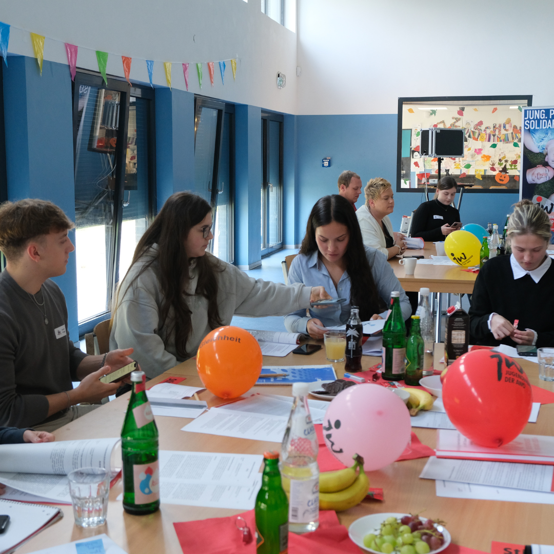 Mitglieder und Delegierte des Jugendwerks sitzen bei der Kreiskonferenz beratend an einem Tisch zusammen.