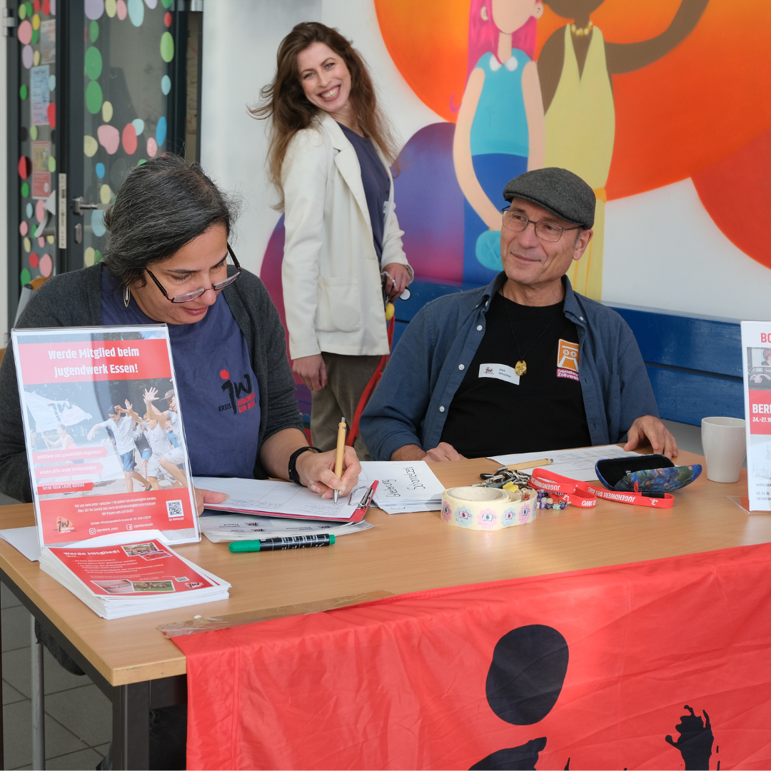 Mitarbeitende des Jugendwerks sitzen am Empfang und empfangen die Gäste der Kreiskonferenz.